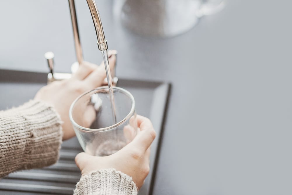 woman holding a water cup under filtered water